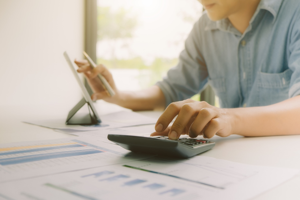 Person Typing on calculator with Graphs on Table